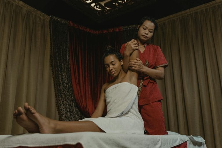 A soothing spa session with a woman receiving a massage indoors, wrapped in a towel.